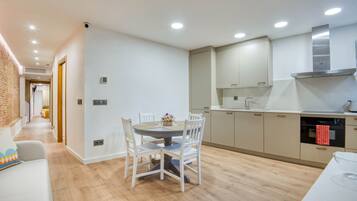 Een moderne keuken met witte kasten, een eettafel met stoelen en een bakstenen muur.