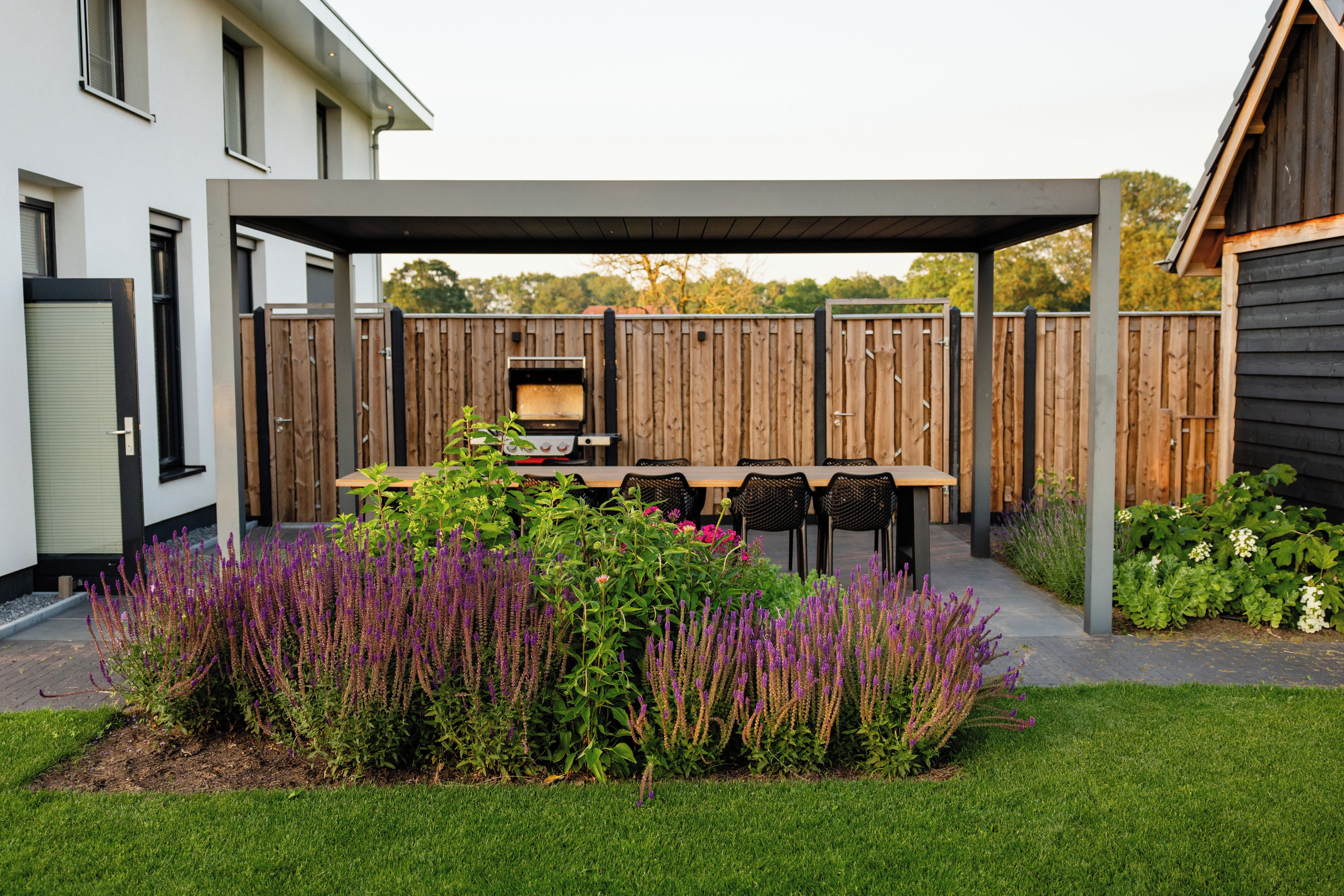 Un patio con una parrilla, mobiliario exterior y una valla de madera.