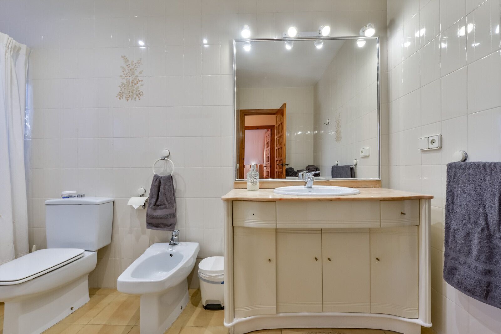 Une salle de bain équipée de toilettes, d’un bidet, d’un lavabo et d’un miroir.