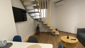 A modern living room with a dining area, a staircase, and a sofa. - Living Yard Acropolis Apartments (Athens)