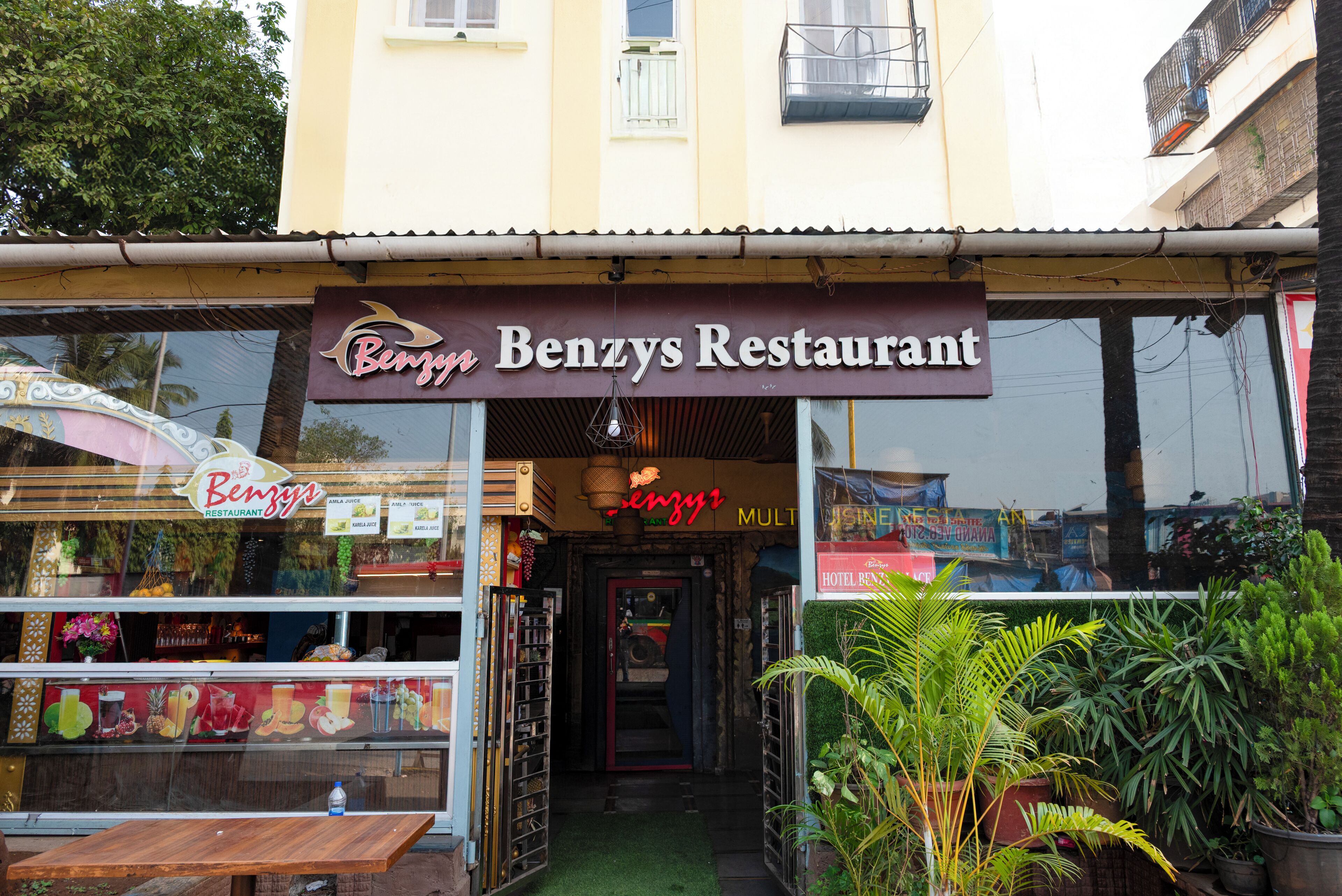 L’extérieur du restaurant Benzys, avec une entrée bien visible, une enseigne et des plantes en pot devant l’établissement.