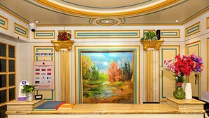 Ein Empfangsschalter mit einem Landschaftsbild, einer Hinweistafel zur Auscheckzeit und einer Blumenkomposition.