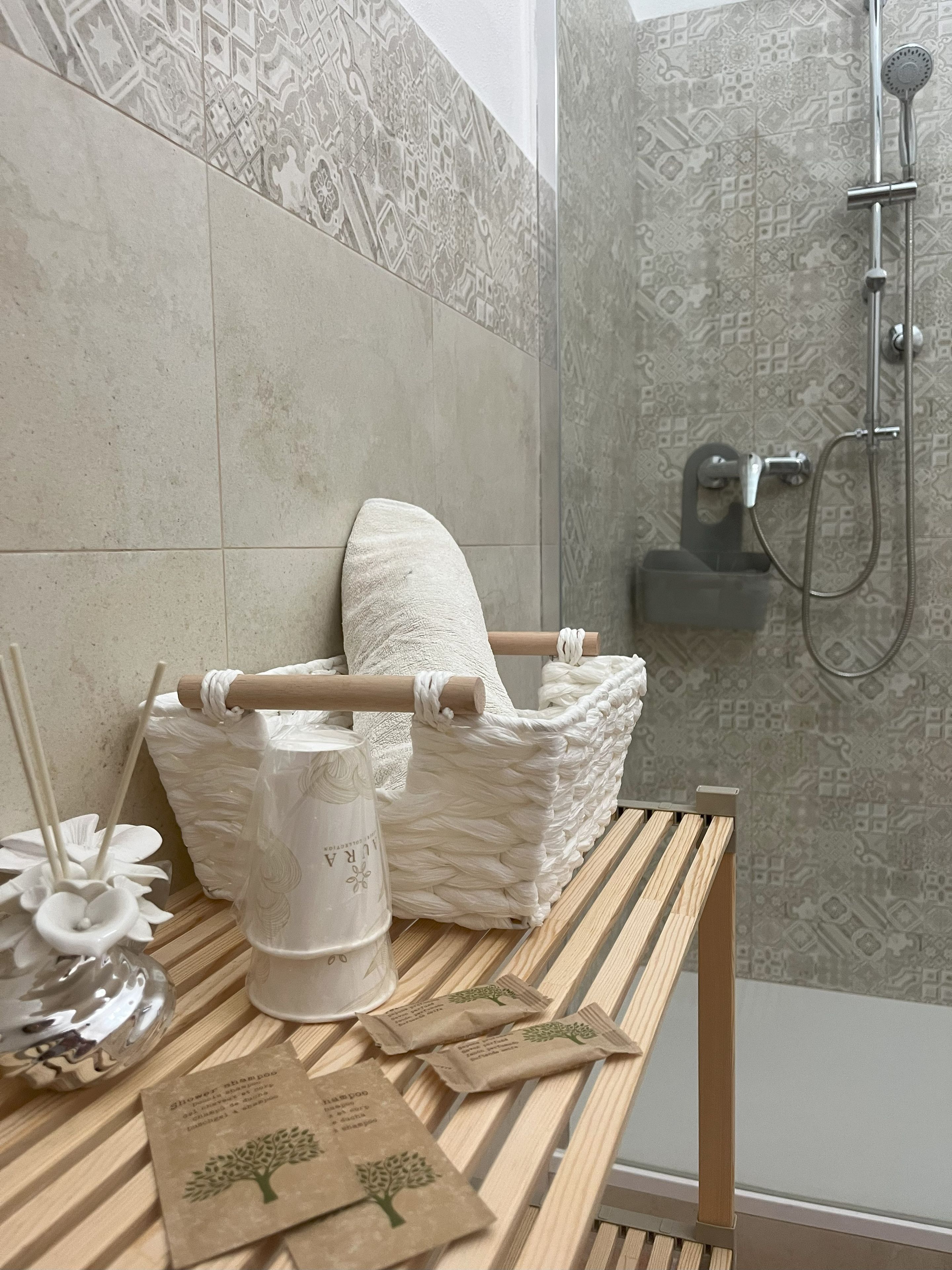 Un bagno con doccia, una panca in legno, un asciugamano e articoli da toilette.