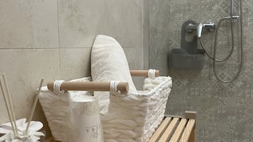 Un bagno con doccia, una panca in legno, un asciugamano e articoli da toilette.