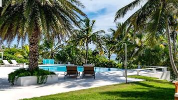A pool area with lounge chairs, a small pool, and palm trees.