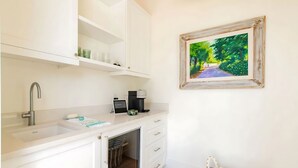 Una cocina moderna con armarios blancos, un lavamanos integrado y una cafetera.