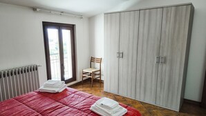 Een slaapkamer met een bed, een kledingkast, een stoel en een radiator.