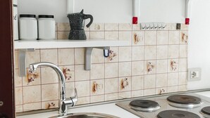 Een keuken met een roestvrijstalen spoelbak, een fornuis en een wit aanrecht.