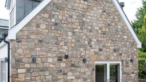 A modern building with a stone facade, a glass door entrance, and a tiled patio area. - Our Cosy Cottage in Gatehouse of Fleet (Gatehouse of Fleet)
