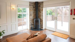 A room with a stone fireplace, a brown leather sofa, and a glass door leading outside.