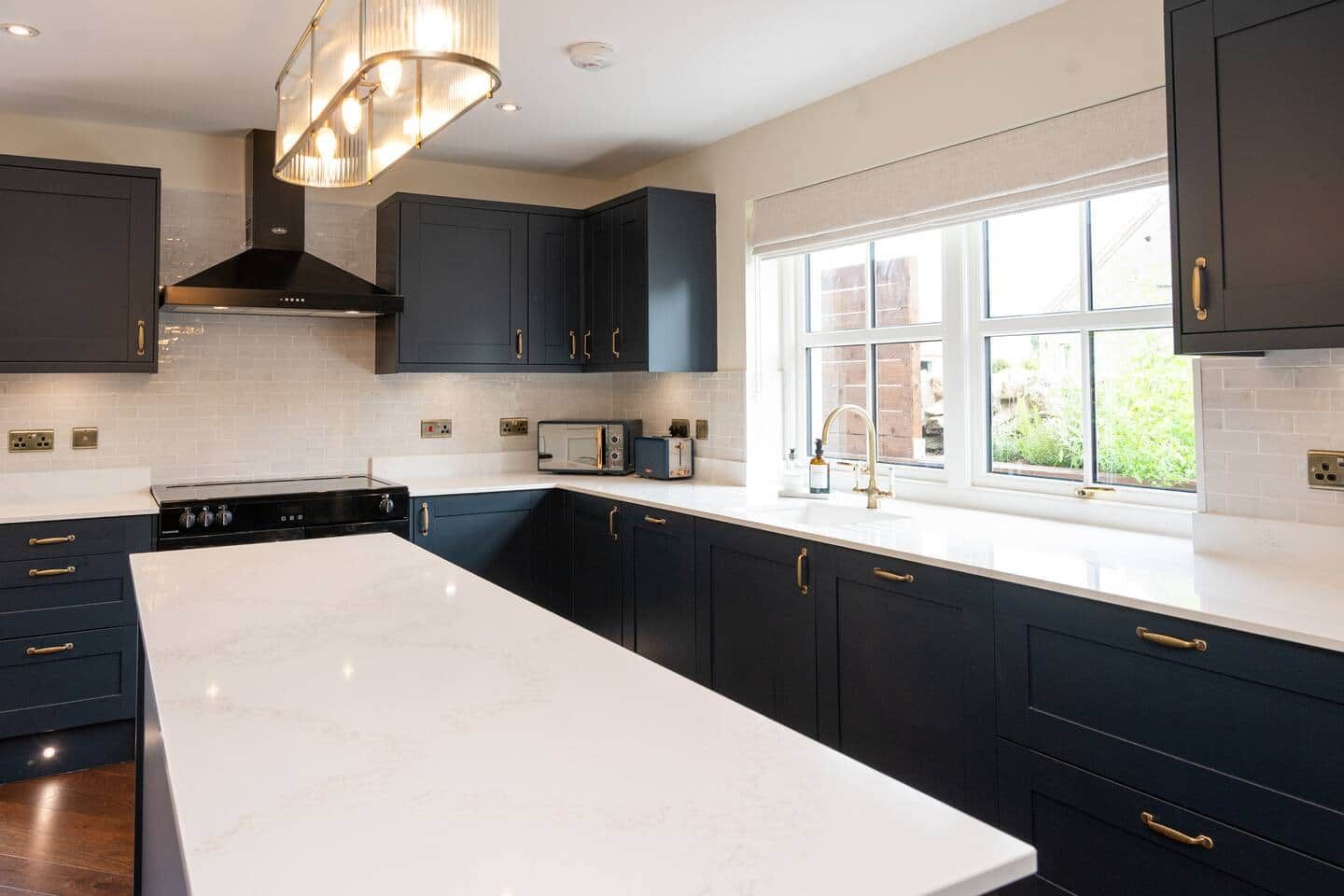 A modern kitchen with dark cabinetry, a large island, and a window providing natural light.