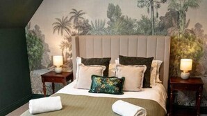 A bedroom with a large bed, two bedside tables with lamps, a headboard, and a mural on the wall. - Our Cosy Cottage in Gatehouse of Fleet (Gatehouse of Fleet)