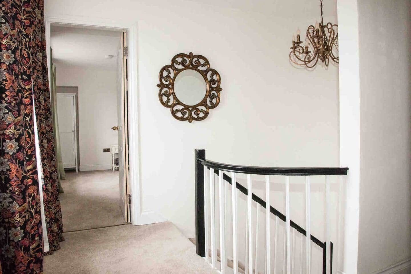 Eine Treppe mit schwarzer Geländer, ein dekorativer Spiegel an der Wand und ein Chandelier.