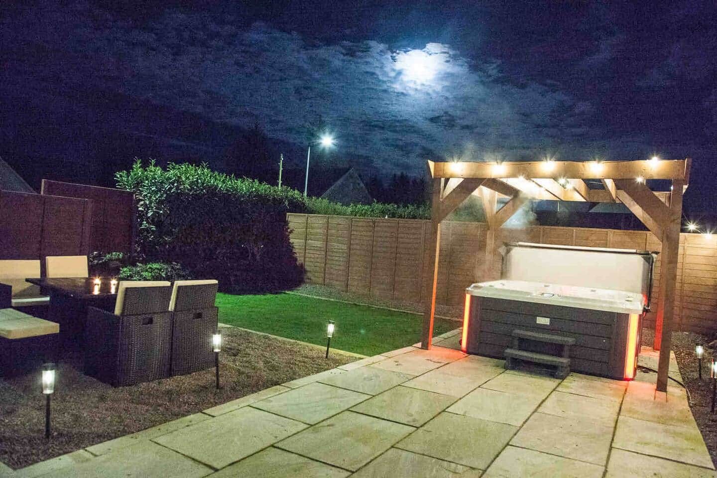 A patio with outdoor seating, a hot tub, and a pergola with string lights.