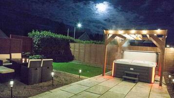 A patio with outdoor seating, a hot tub, and a pergola with string lights.