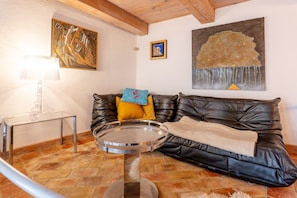 A living room with a leather sofa, a round coffee table, and artwork on the walls. - Le Cocon – Cozy Village House with Mountain Views (Puimoisson)