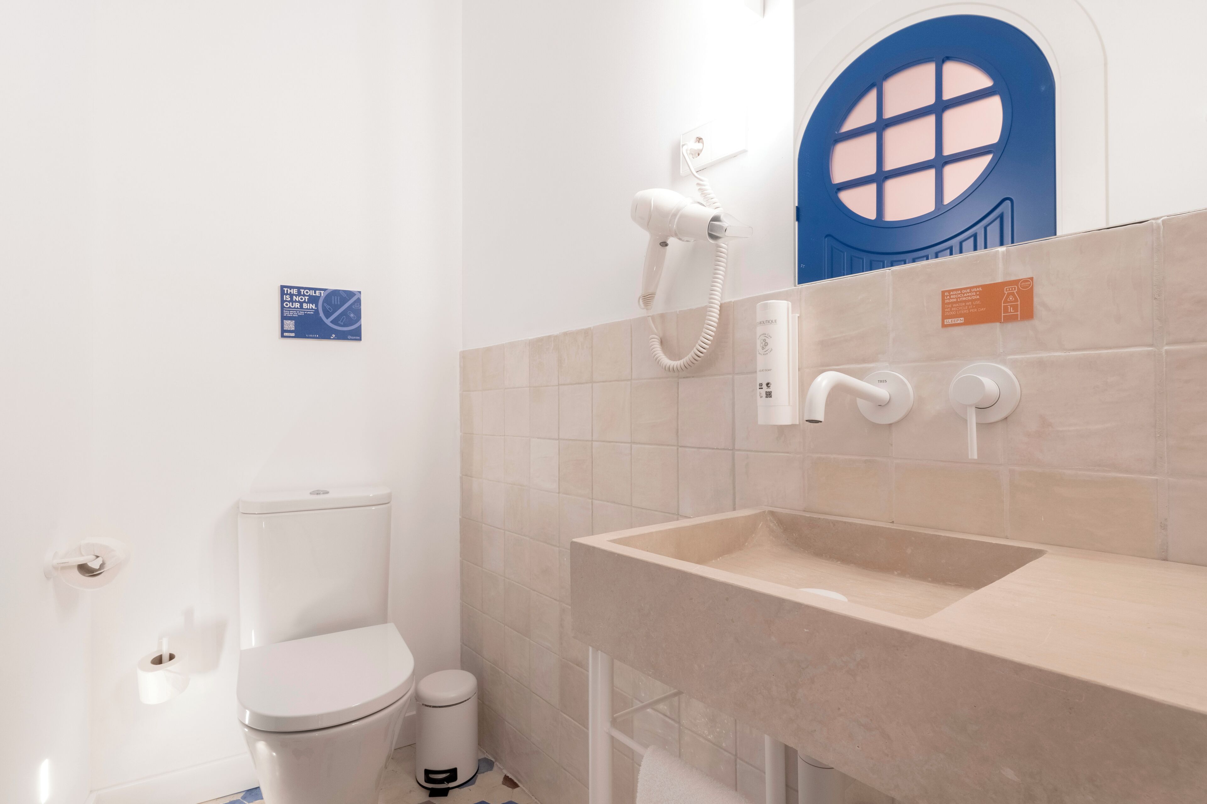 A bathroom with a toilet, a hand dryer, a sink, and a blue door.
