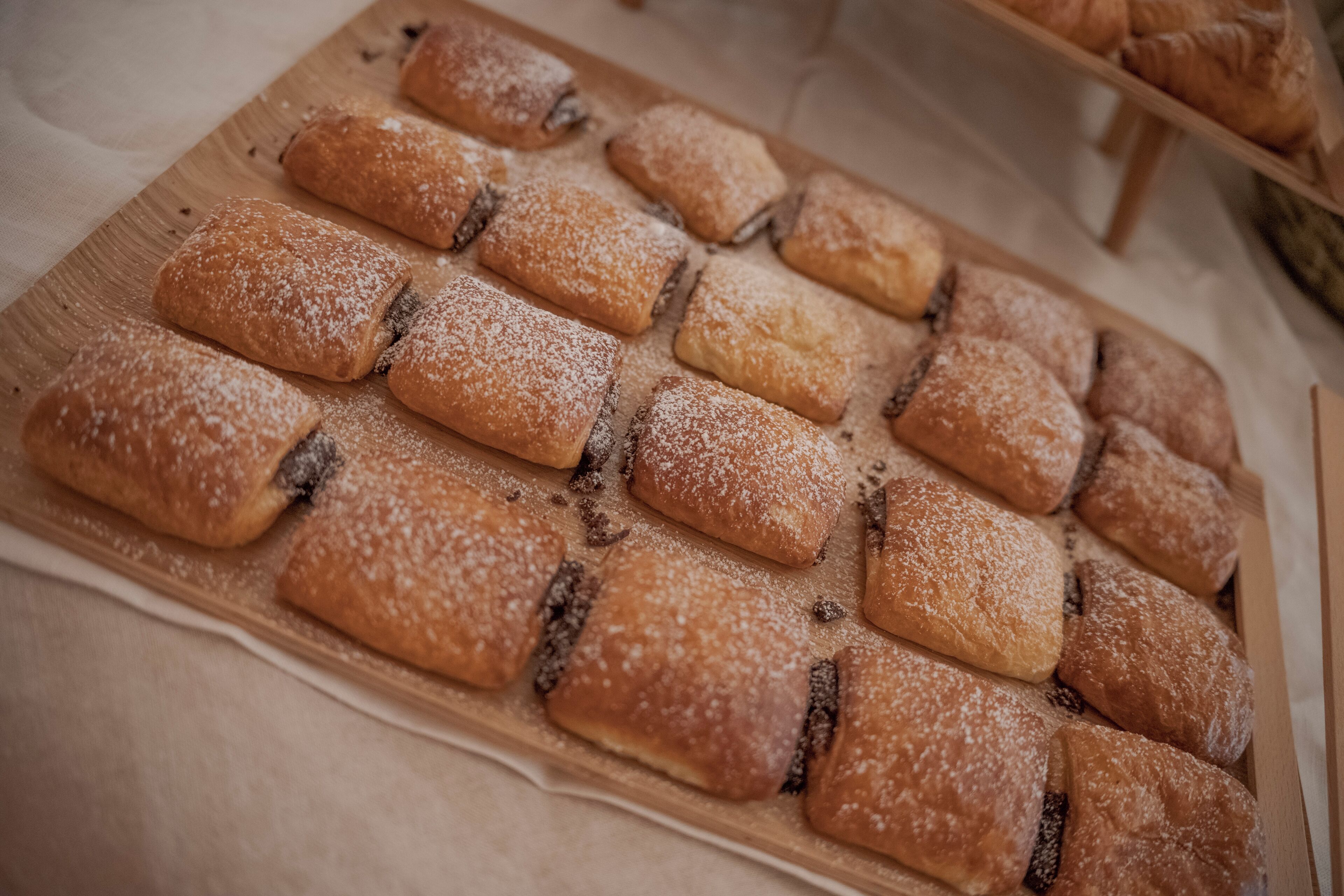A wooden board with rectangular pastries dusted with powdered sugar.