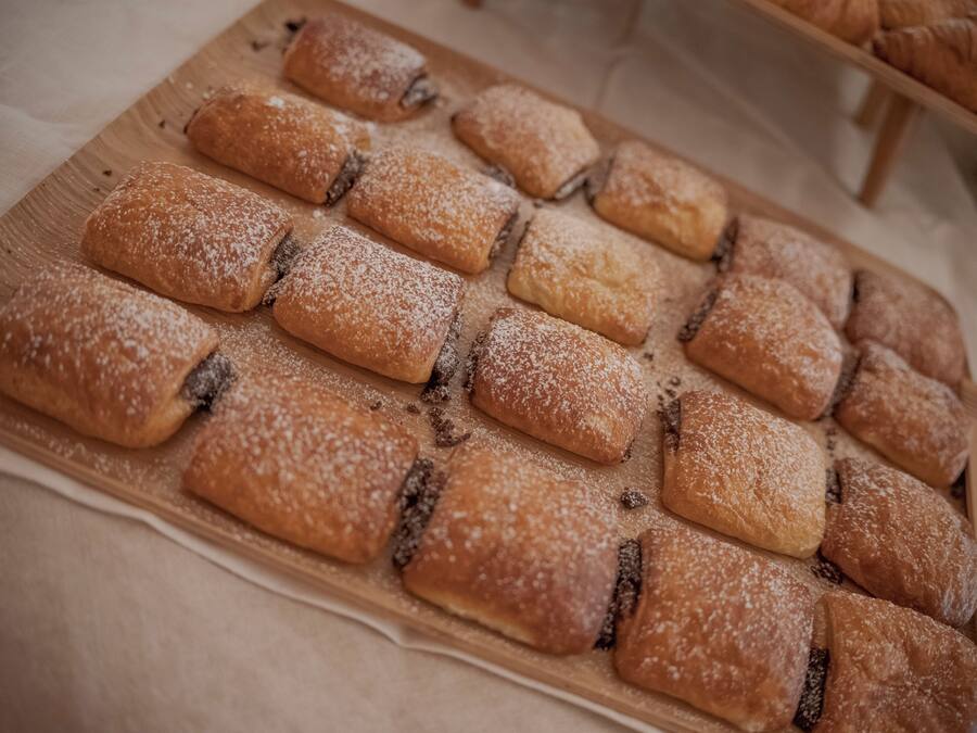 A wooden board with rectangular pastries dusted with powdered sugar.