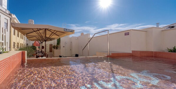 A rooftop pool area with a sun umbrella labeled 'SLEEPN' and a staircase leading to an upper level. - SLEEPN Valencia (Valencia)