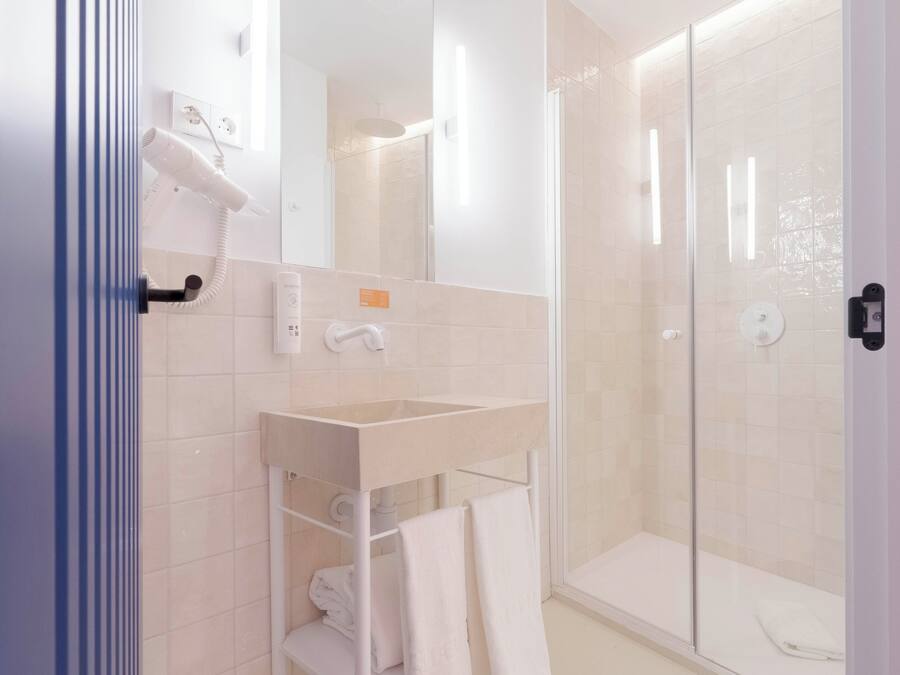 A modern bathroom with a glass shower enclosure, a white sink, and a towel rack.
