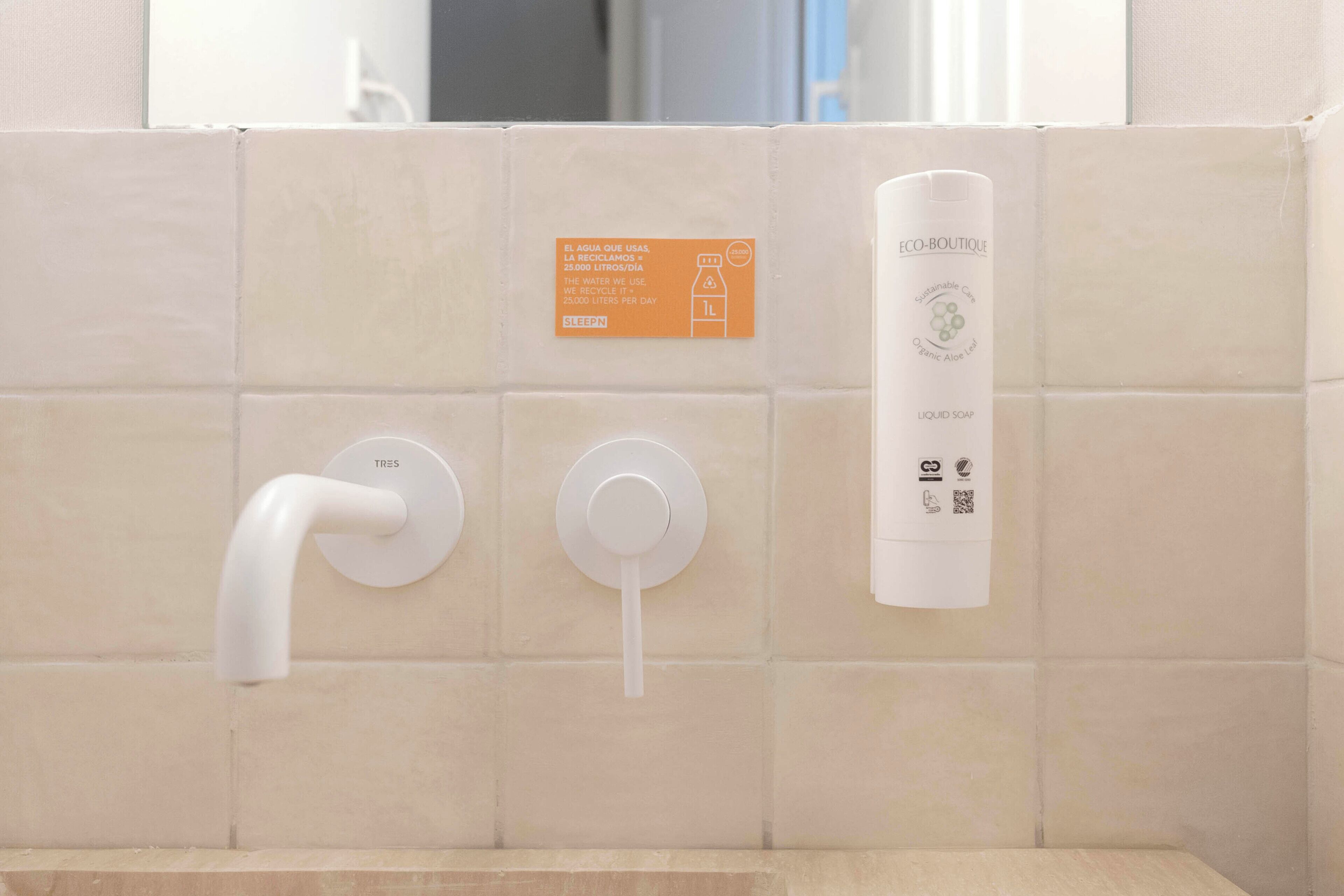 A bathroom with a white toilet, a bidet, and a soap dispenser.