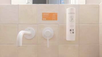 A bathroom with a white toilet, a bidet, and a soap dispenser.