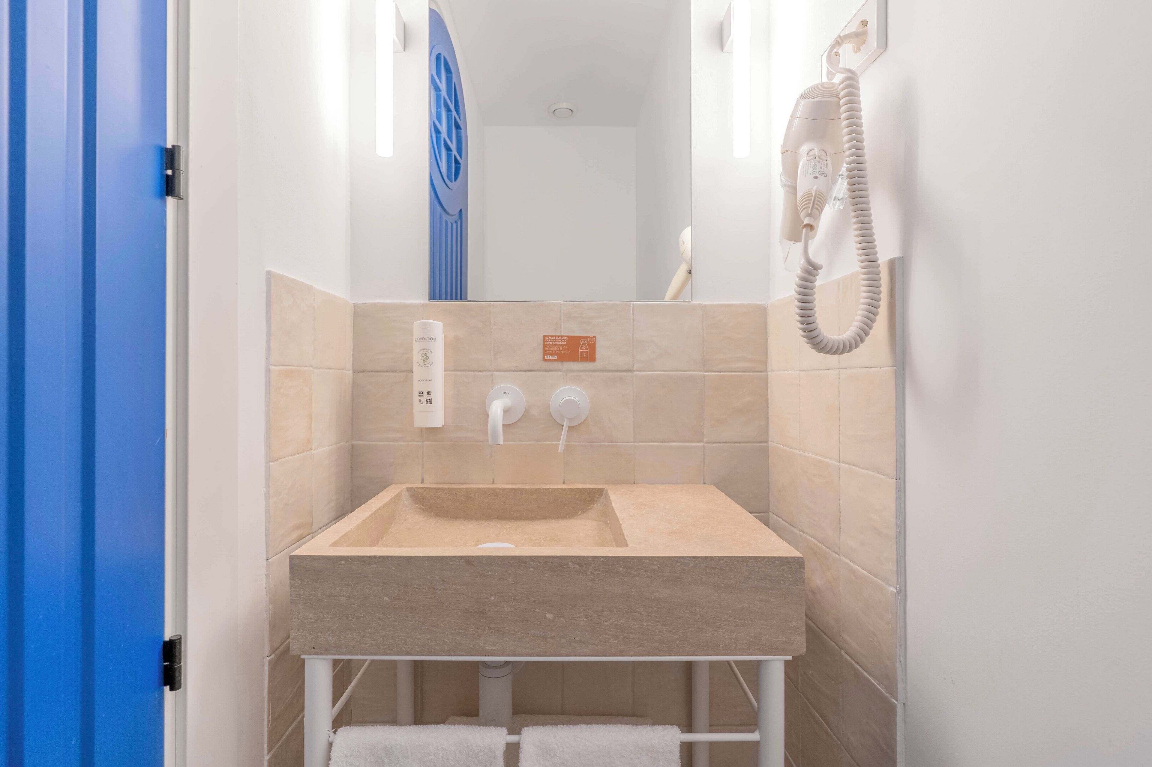 A bathroom with a beige sink, two faucets, a towel rack, and a telephone.