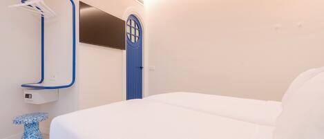 Habitación de hotel moderna con cama, una puerta azul, televisor montado en la pared y un toallero azul.