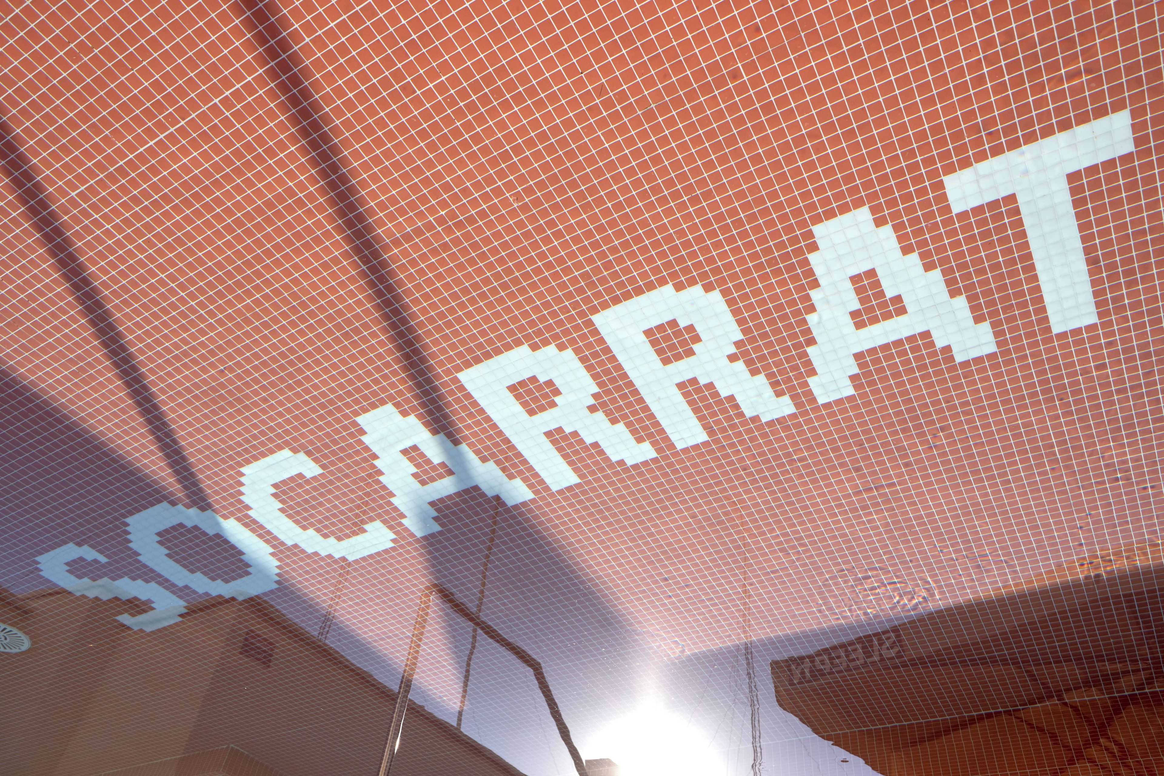 A close-up of a red-tiled wall with a white grid pattern and the word 'SOCARRAT' in large letters.