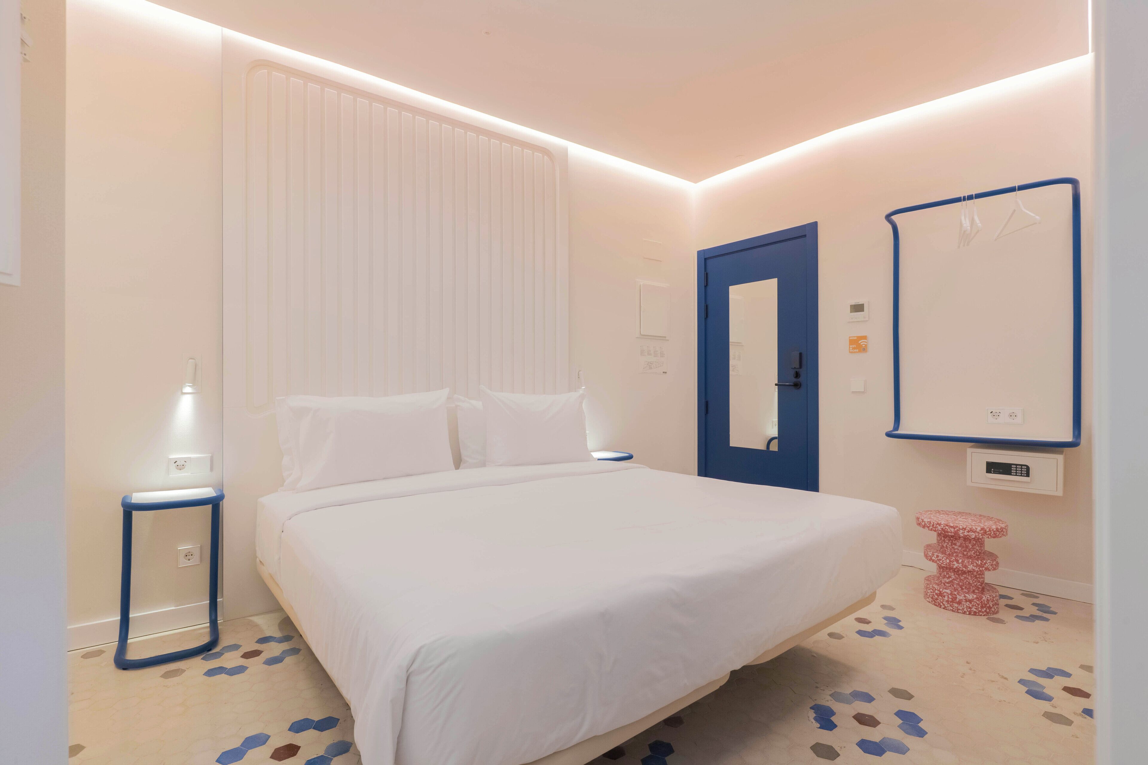 Un dormitorio con cama, mesita de noche y espejo en la pared.
