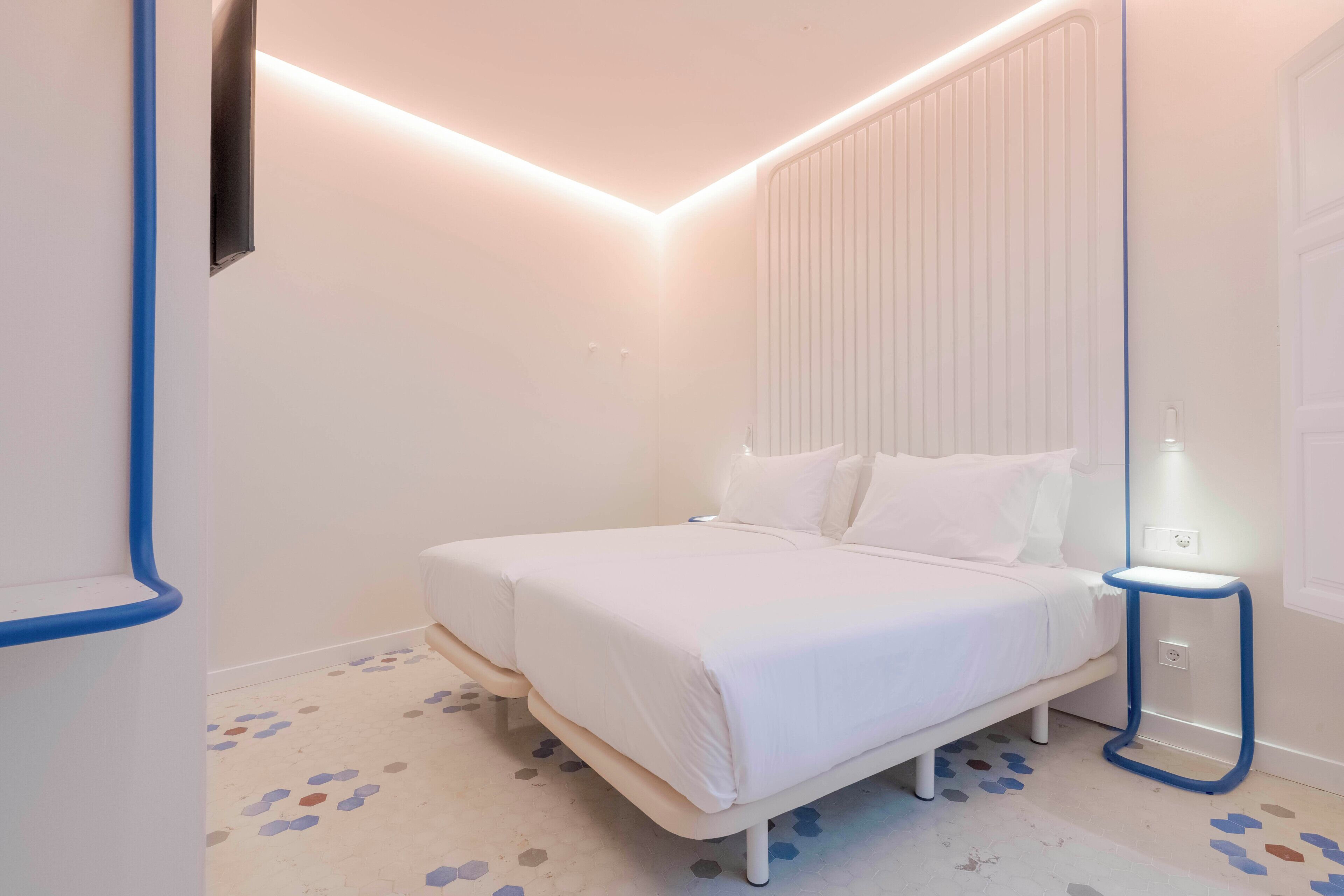 A bedroom with a bed, bedside table, and a wall-mounted TV.