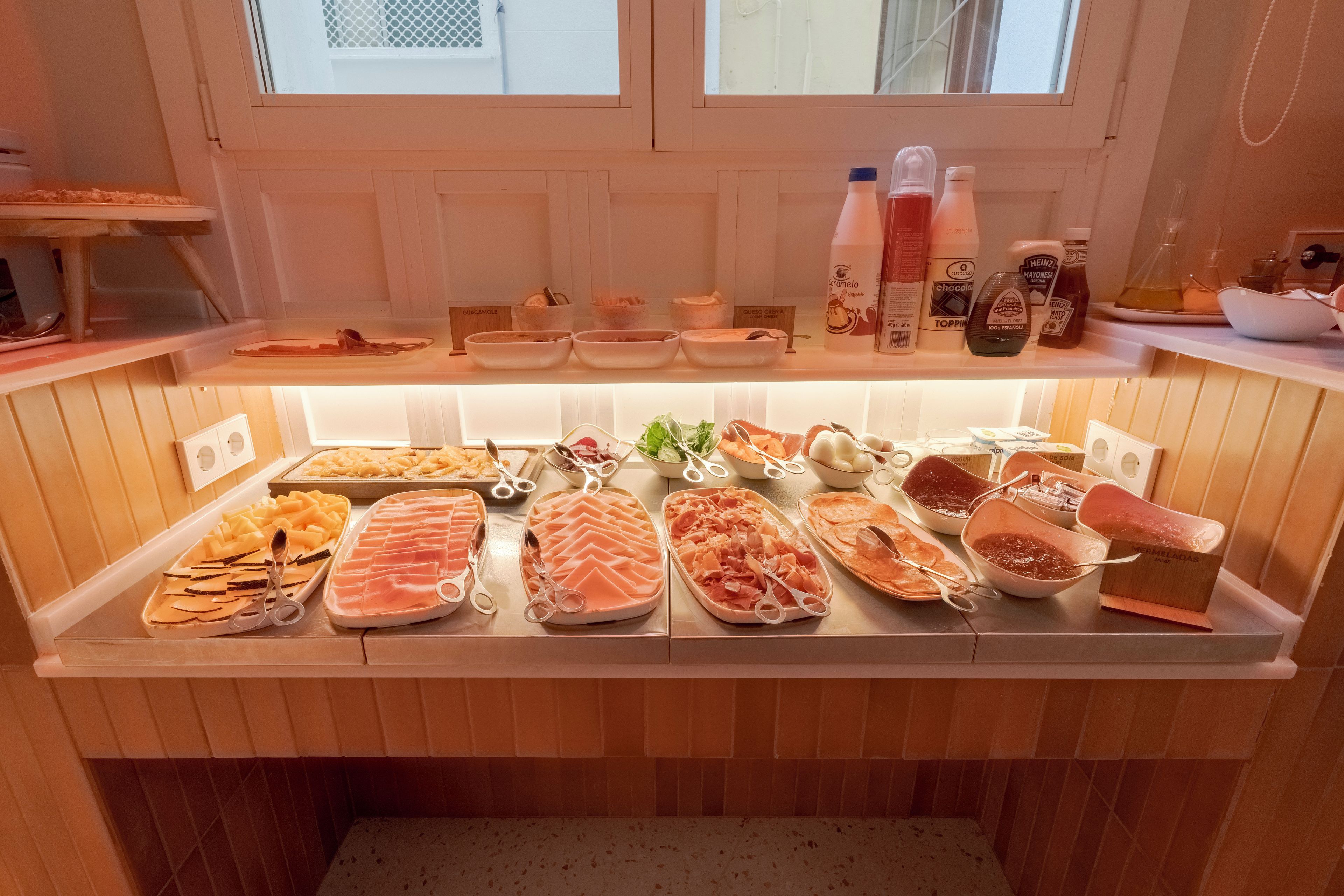 A food display with various cheeses, meats, and condiments.