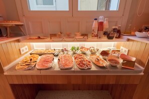 A food display with various cheeses, meats, and condiments.