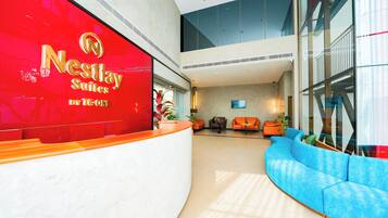 Een hotel receptie met een gebogen balie, een blauwe bank en een groot raam.