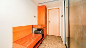 Ein kleines Zimmer mit einem Holzbett, einem kleinen Schreibtisch und einer Tür zu einem weiteren Raum.