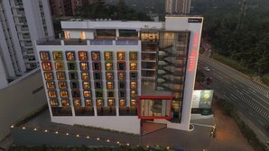 Ein modernes Hotel mit einer einzigartigen Fassade, die farbenfrohe Fensterrahmen und einen markanten Eingang mit rotem Akzent zeigt. Eine Schilderung weist 'Palmetto Westley Suites' aus.