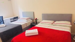 Quarto de hotel com duas camas de solteiro, uma mesa e uma cadeira.