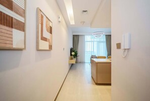 Un moderno vestíbulo de hotel con una recepción, una zona de comedor y un pasillo que conduce a las habitaciones.