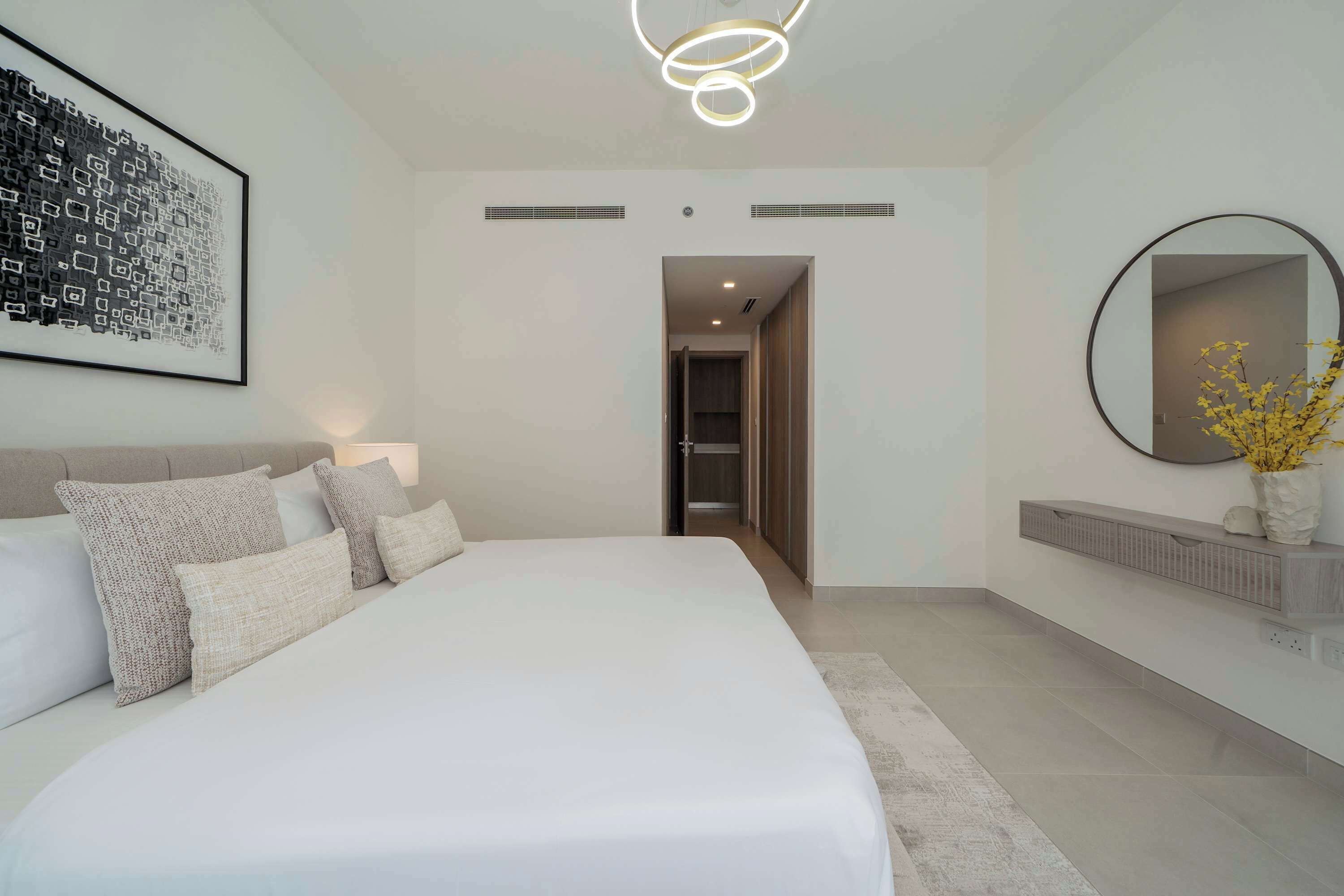 Una camera da letto moderna con un letto grande, uno specchio a parete e un'opera d'arte incorniciata.
