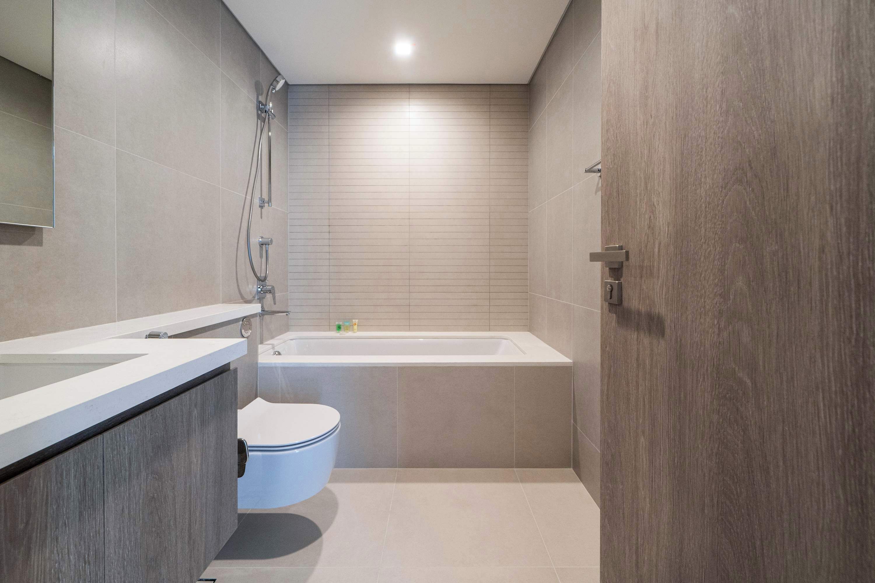 A modern bathroom with a bathtub, toilet, and vanity.