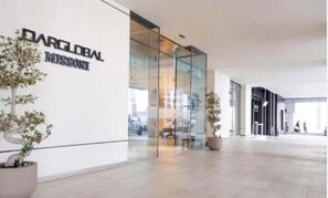 A modern building with a glass facade and signage for 'DARGLOBAL MISSION'. - Elegant High Floor 2BR Furnished Urban Oasis (Dubai)