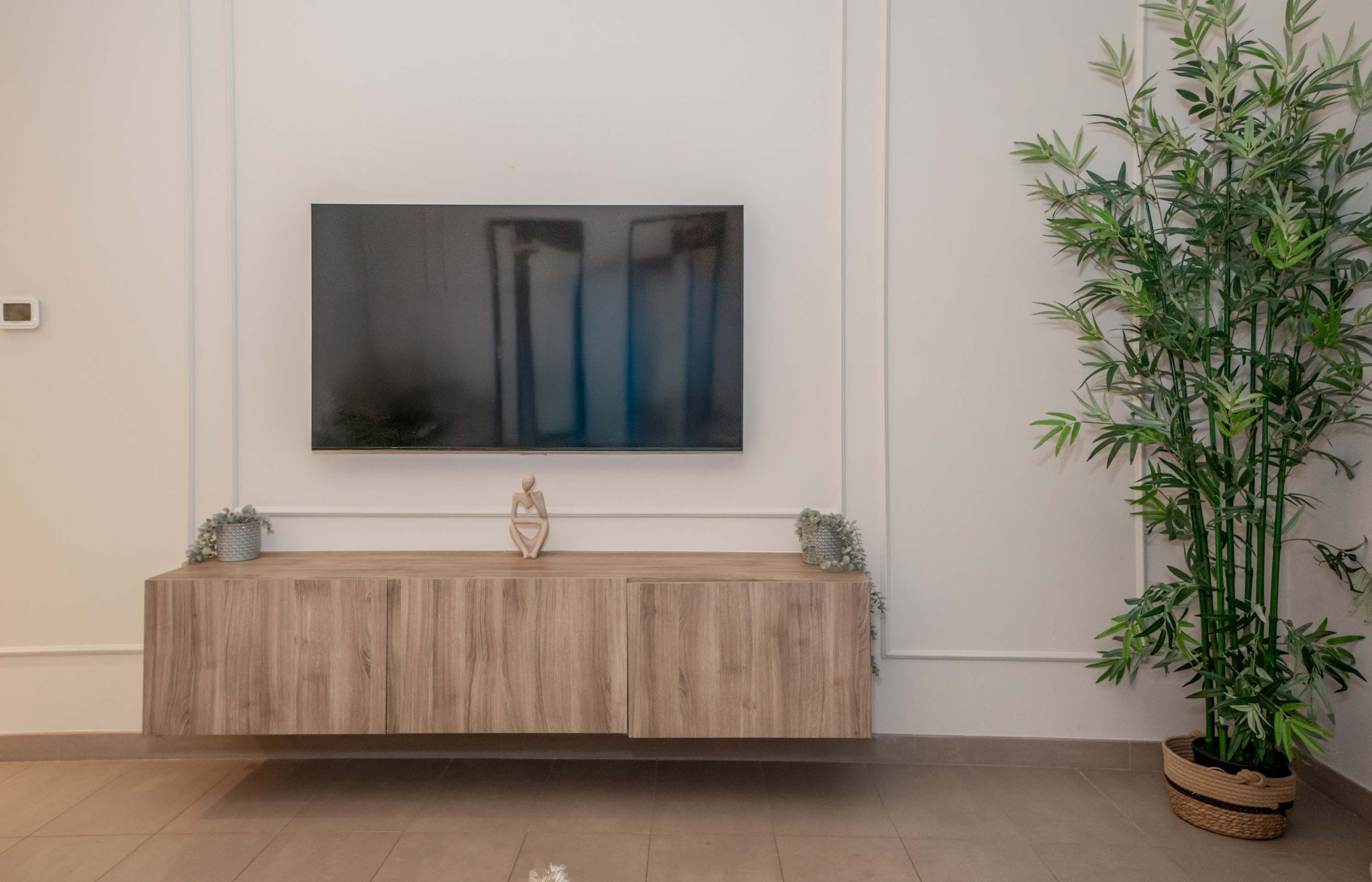 Habitación minimalista con una consola de madera, un cuadro abstracto en la pared y una planta de bambú.
