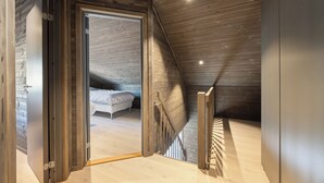 A modern loft bedroom with a sloped ceiling, a wooden staircase, and a bed with white bedding. - Berre Veit 6p (Kviteseid)