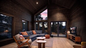 A cozy interior with a wooden ceiling, a sofa, a chair, a small table, and a TV. - Berre Veit 6p (Kviteseid)
