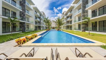 Una piscina al aire libre, sillones reclinables de piscina