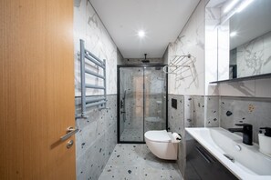 Une salle de bain moderne avec une douche à parois de verre, des toilettes et un lavabo avec un miroir.