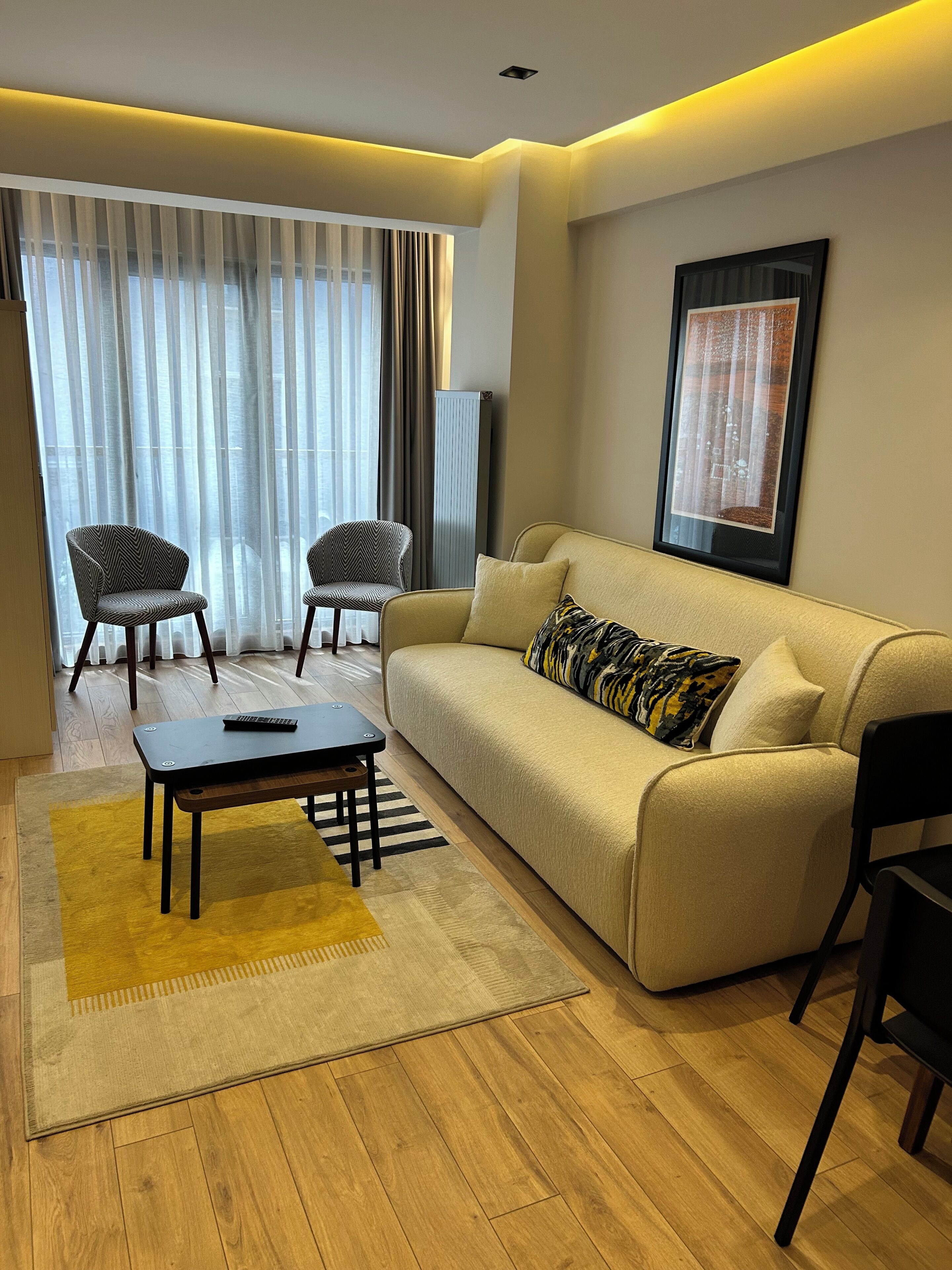 A modern living room with a sofa, two armchairs, a coffee table, and a flat-screen TV.