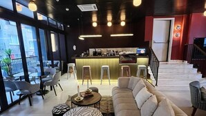 Ένας μοντέρνος εσωτερικός χώρος με έναν καναπέ, στρογγυλά τραπέζια και μια περιοχή με μπαρ.
