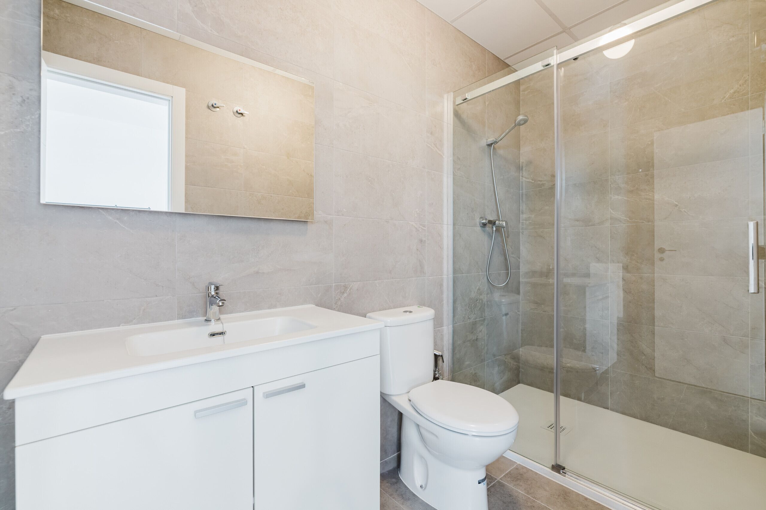 A bathroom with a white sink, toilet, and glass shower enclosure.